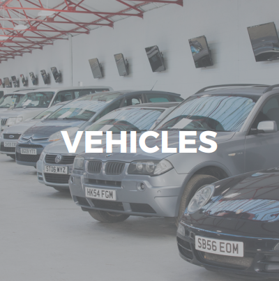 low brightness saleroom displaying a mix of cars with a title in white lettering that reads Vehicles