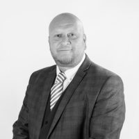 grey filtered headshot of Steve Anderson in suit and tie